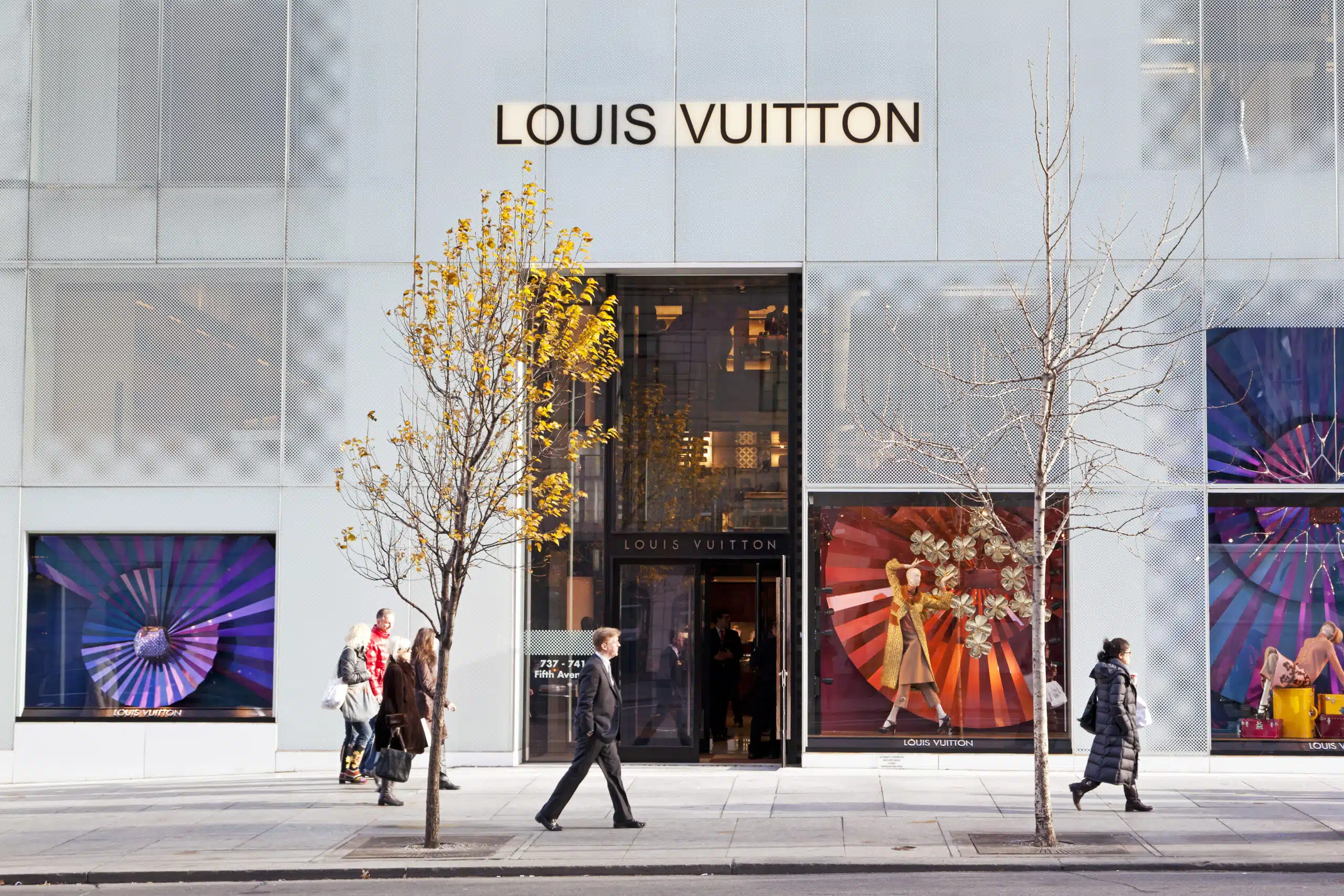 People walking on the sidewalk in front of the Louis Vuitton store at Fifth avenue